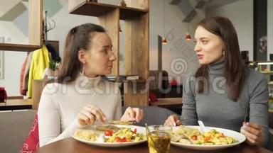 两个女朋友在咖啡馆里<strong>一起吃</strong>饭，聊天，享受他们的<strong>食物</strong>。